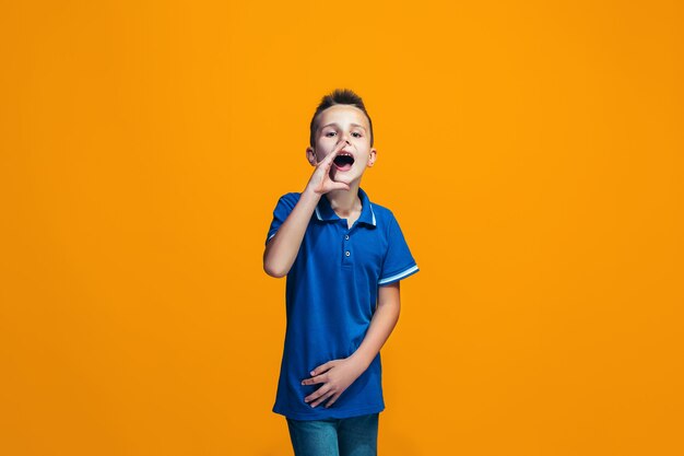 Isolated on orange young casual teen boy shouting