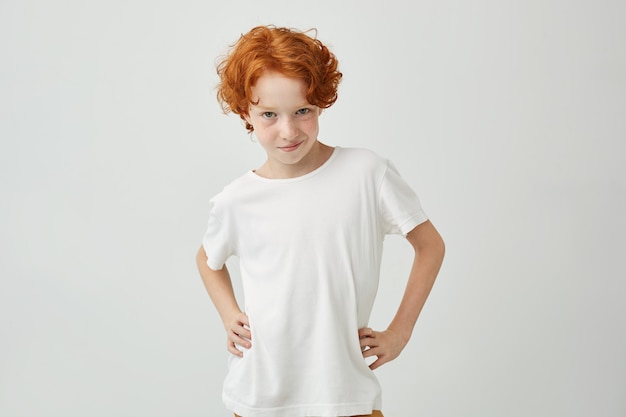 허리에 손을 잡고 흰색 셔츠에 재미 생강 소년의 고립 된 초상화