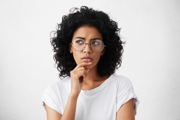 isolated portrait of stylish young mixed race woman with dark shaggy hair touching her chin
