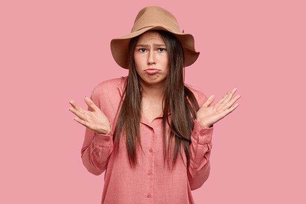 Isolated shot of displeased brunette woman purses lips, cant make right decision