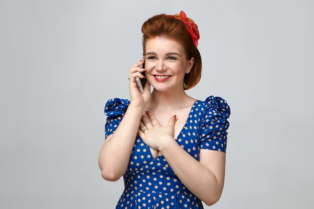 Free photo isolated shot of gorgeous emotional young european woman wearing elegant vintage clothes smiling happily, holding hand on her chest,