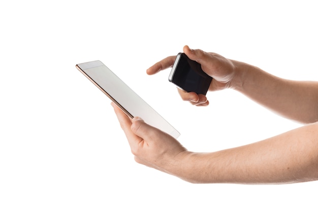 Isolated shot of hands holding a tablet and a phone on white wall