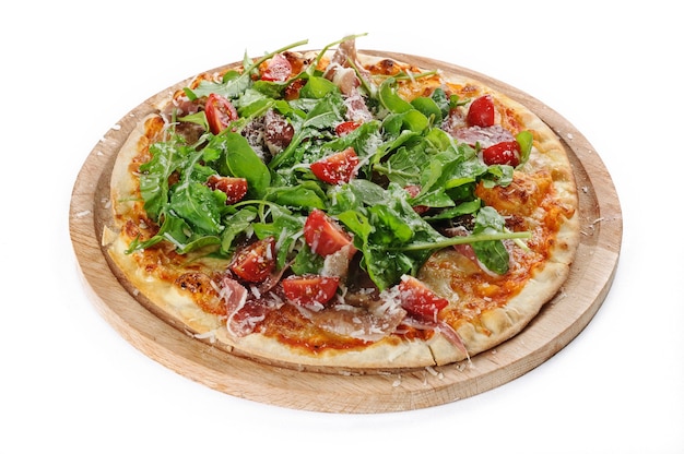 Isolated shot of a pizza with ham and arugula