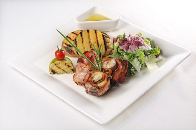 Isolated shot of a plate with pork with tomatoes and salad