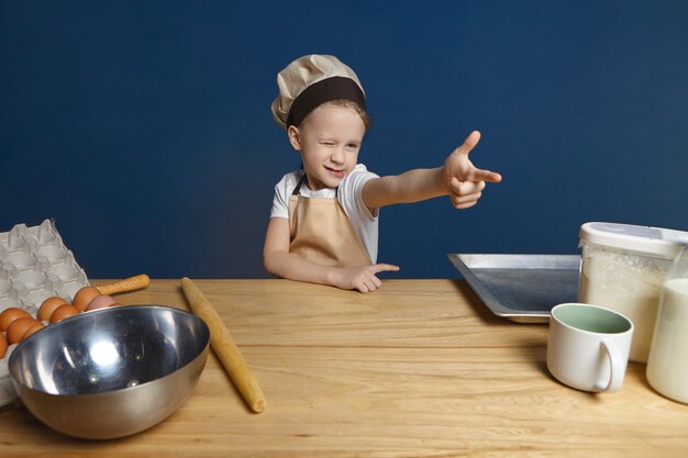 エプロンと帽子のウィンクで遊び心のあるかわいい男性の子供の孤立したショット