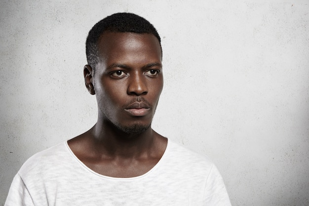 Free photo isolated shot of stylish fashionable african model dressed in white t-shirt with serious expression.