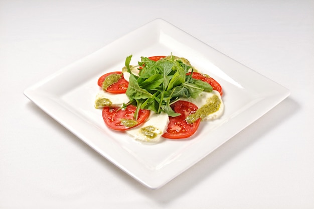Isolated shot of a white plate with Caprese salad - perfect for a food blog or menu usage