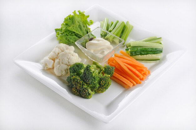Isolated shot of a white plate with sliced vegetables with white sauce