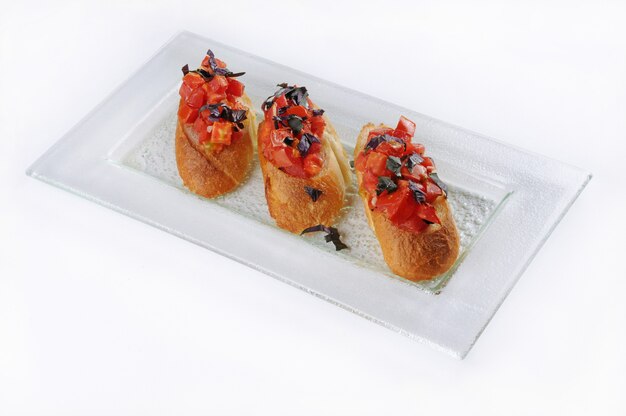 Isolated shot of a white plate with three classic bruschettas