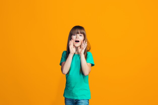 Isolated on yellow young casual teen girl shouting at studio