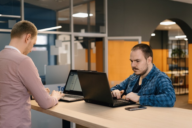 IT coders working on the laptop in the office standing at the table