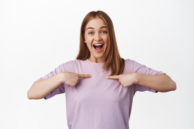 Free photo it is me. happy young woman excited, pointing at herself with thrilled surprised smile, choose her gesture, bragging, achieve goal, standing over white background