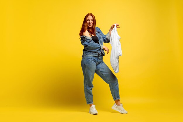 フォロワーになるのは簡単です。シャツが1枚だけの場合は、洗濯が速くなります。黄色の背景に白人女性の肖像画。美しい赤い髪のモデル。人間の感情、顔の表情、販売、広告の概念。