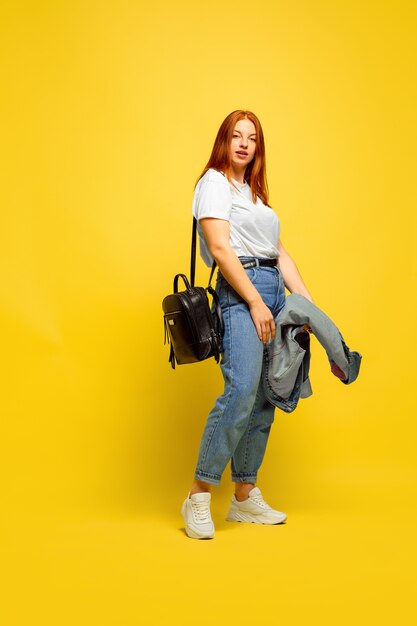 It's easier to be follower. Need minimum clothes to go. Caucasian woman's portrait on yellow background. Beautiful female red hair model. Concept of human emotions, facial expression, sales, ad.