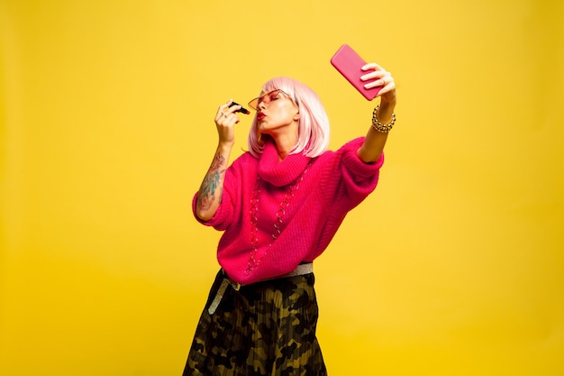 It's hard to be influencer. Can't make up without selfie or vlog. Caucasian woman's portrait on yellow background. Beautiful blonde model. Concept of human emotions, facial expression, sales, ad.