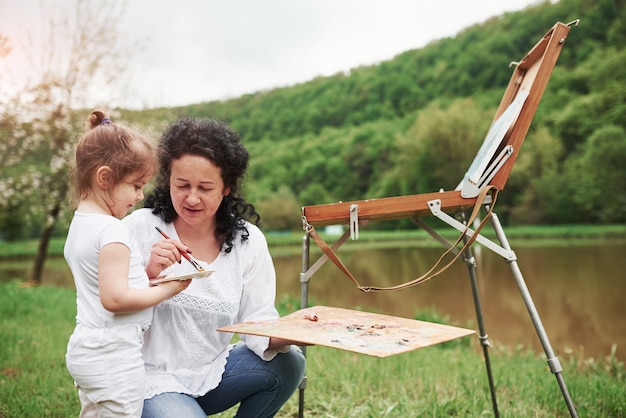 Foto gratuita non è così difficile. insegnare alla nipote a dipingere. nel parco naturale