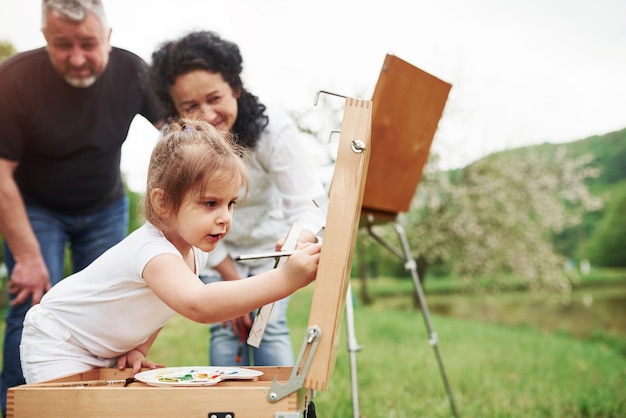 Free photo it's will look awesome. grandmother and grandfather have fun outdoors with granddaughter. painting conception