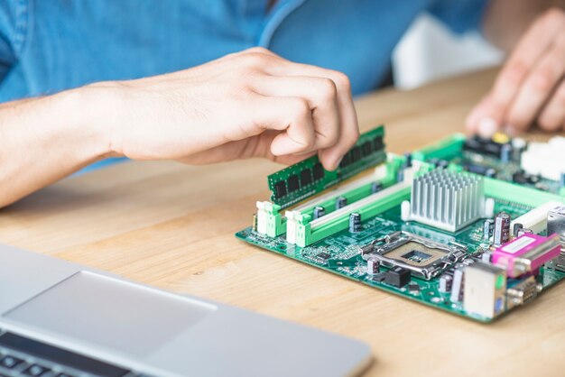 It technician repairing hardware equipment's on wooden table