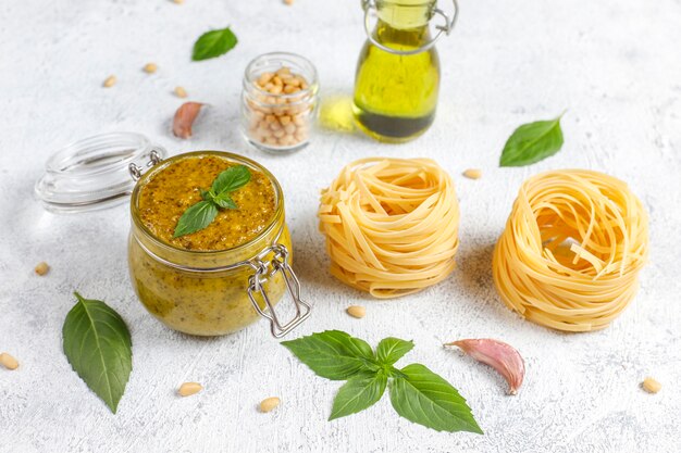 Italian basil pesto sauce with culinary ingredients for cooking.