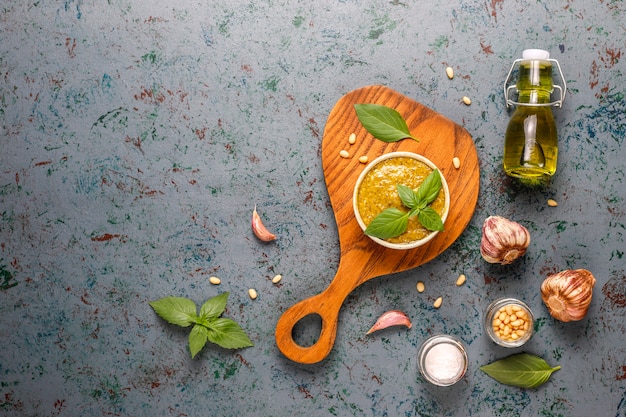 Italian basil pesto sauce with culinary ingredients for cooking.