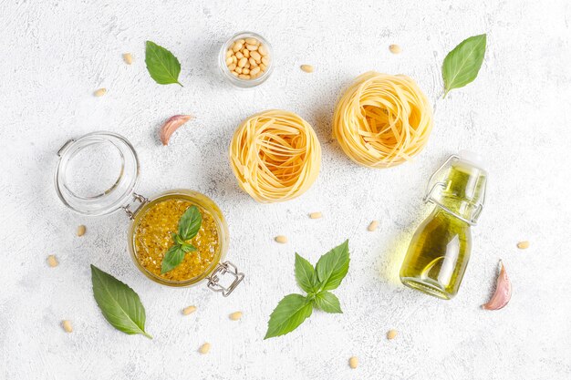 Italian basil pesto sauce with culinary ingredients for cooking.
