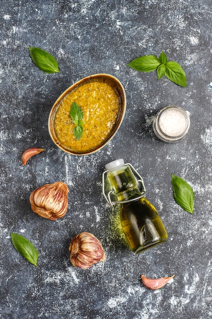 Italian basil pesto sauce with culinary ingredients for cooking.