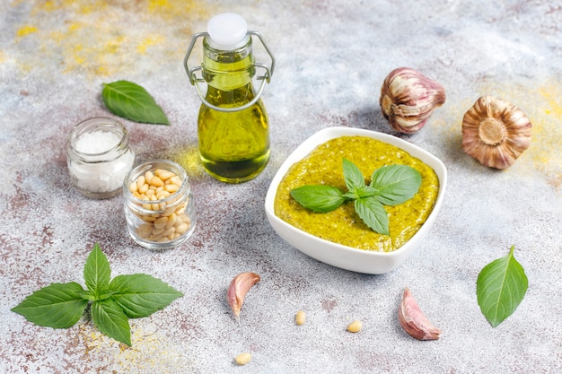 Italian basil pesto sauce with culinary ingredients for cooking.