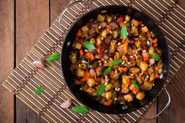 Italian Caponata with frying pan on a wooden table