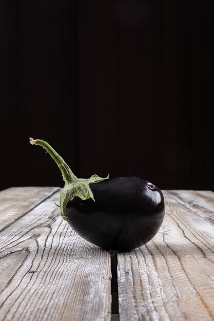 Italian eggplant on a wooden and black . side view.