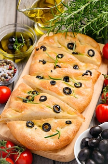 オリーブ​と​素朴な​木製​の​背景​に​ローズマリー​の​イタリア​の​フォカッチャ​の​パン​。
