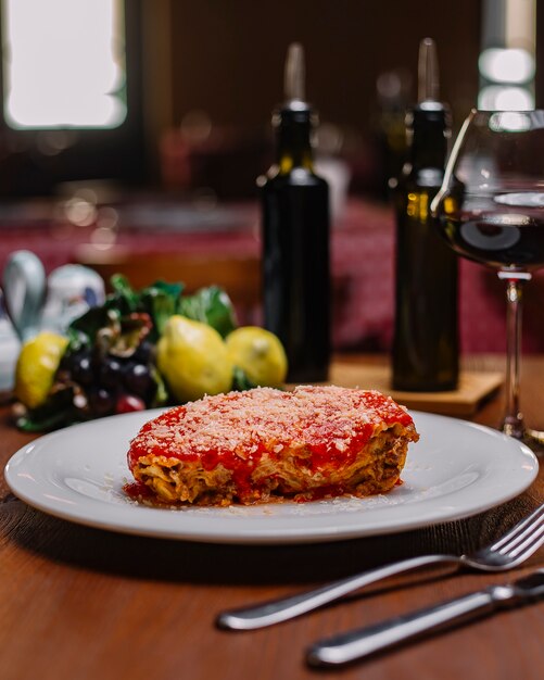 Italian lasagne garnished with tomato sauce and grated parmesan