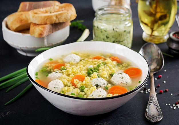 Italian meatball soup and Stelline  gluten free pasta in bowl on black table. Dietary soup. Baby menu. Tasty food.