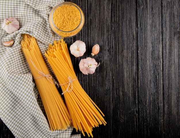 Free photo italian pasta linguini spaghetti garlic on the dark wooden background top view copy space