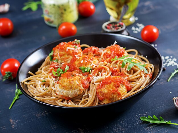 Italian pasta. Spaghetti with meatballs and parmesan cheese in black plate on dark rustic wood background. Dinner. Slow food concept