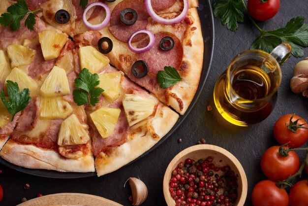 Italian pizza and pizza cooking ingredients on black concrete background.