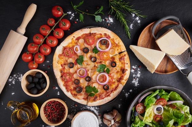 Pizza italiana e ingredienti da cucina pizza sulla superficie di pietra scura