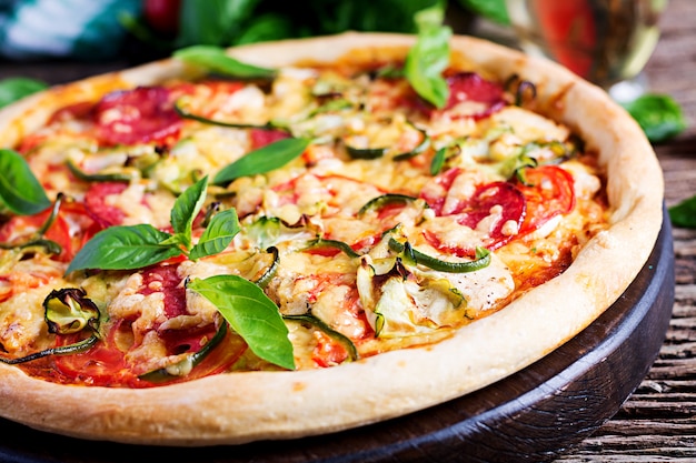 Italian pizza with chicken, salami, zucchini, tomatoes and herbs