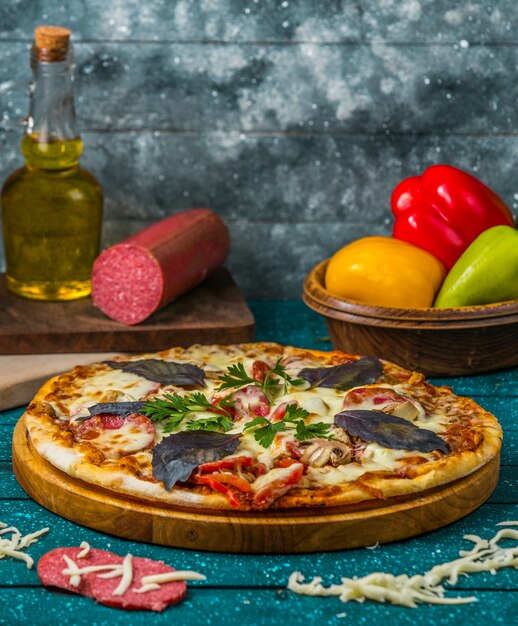 итальянская пицца с колбасой, болгарским перцем, украшенная темным опаловым базиликом и петрушкой