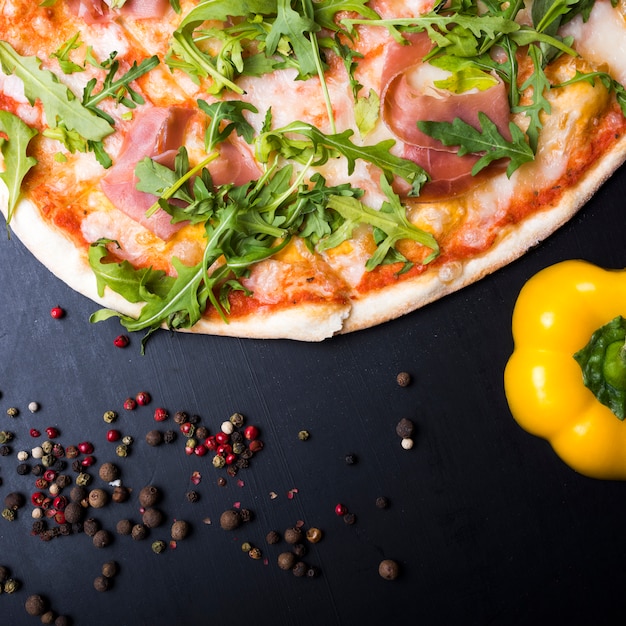 Итальянская пицца; желтый перец и черный перец на кухонном столе