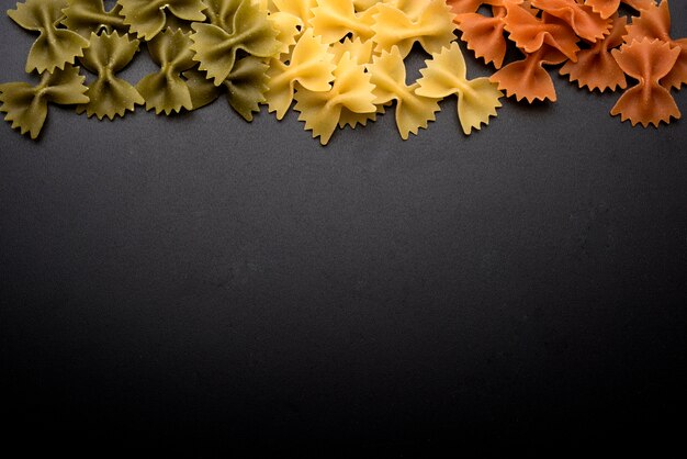 Italian raw fresh bow tie pasta over black background with copy space for writing text