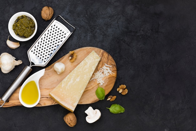 Free photo italian sauce; cheese block; olive oil; walnut; garlic clove; basil and mushroom on stainless steel grater