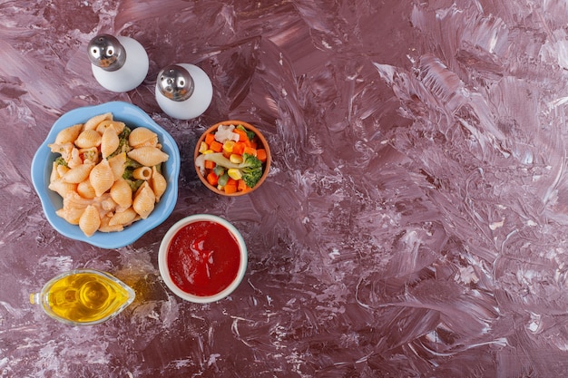 Italian shell pasta with tomato sauce and mixed vegetable salad on light table .