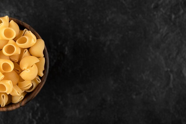 Italian uncooked pasta conchiglie in wooden bowl . 