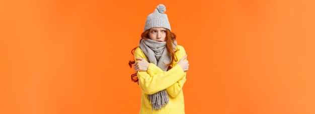 Foto gratuita fuori fa un freddo gelido, una bella ragazza dai capelli rossi che si scuote e si abbraccia per riscaldarsi mentre aspetta qualcuno