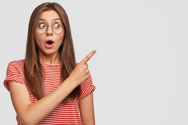 その信じられないほど、見て！彼女の近くにあるものに驚かされている驚いた黒髪の若い女性