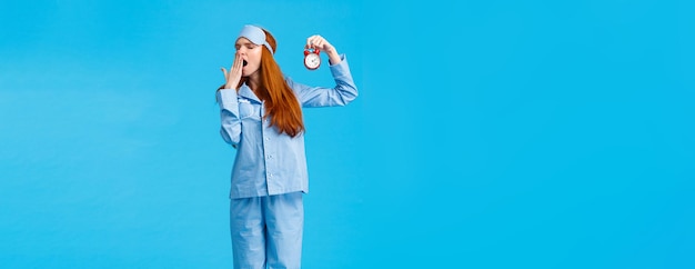 Its so late time to bed tired and sleepy cute redhead female in nightwear and sleep mask holding red