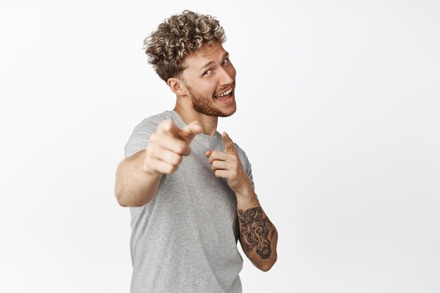 Its you congrats Smiling enthusiastic young man pointing fingers at camera praising you inviting to use company service recruiting to join him white background