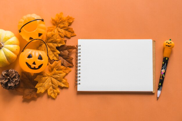 Jack-o-lantern buckets and autumn symbols near notebook and pen