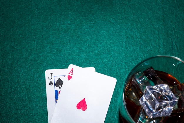 Jack of spade e cuore asso carta da gioco con bicchiere di whisky sul tavolo da poker