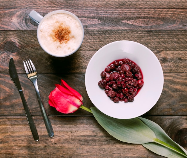 Foto gratuita marmellata in ciotola, fiori freschi, posate e tazza di bevanda